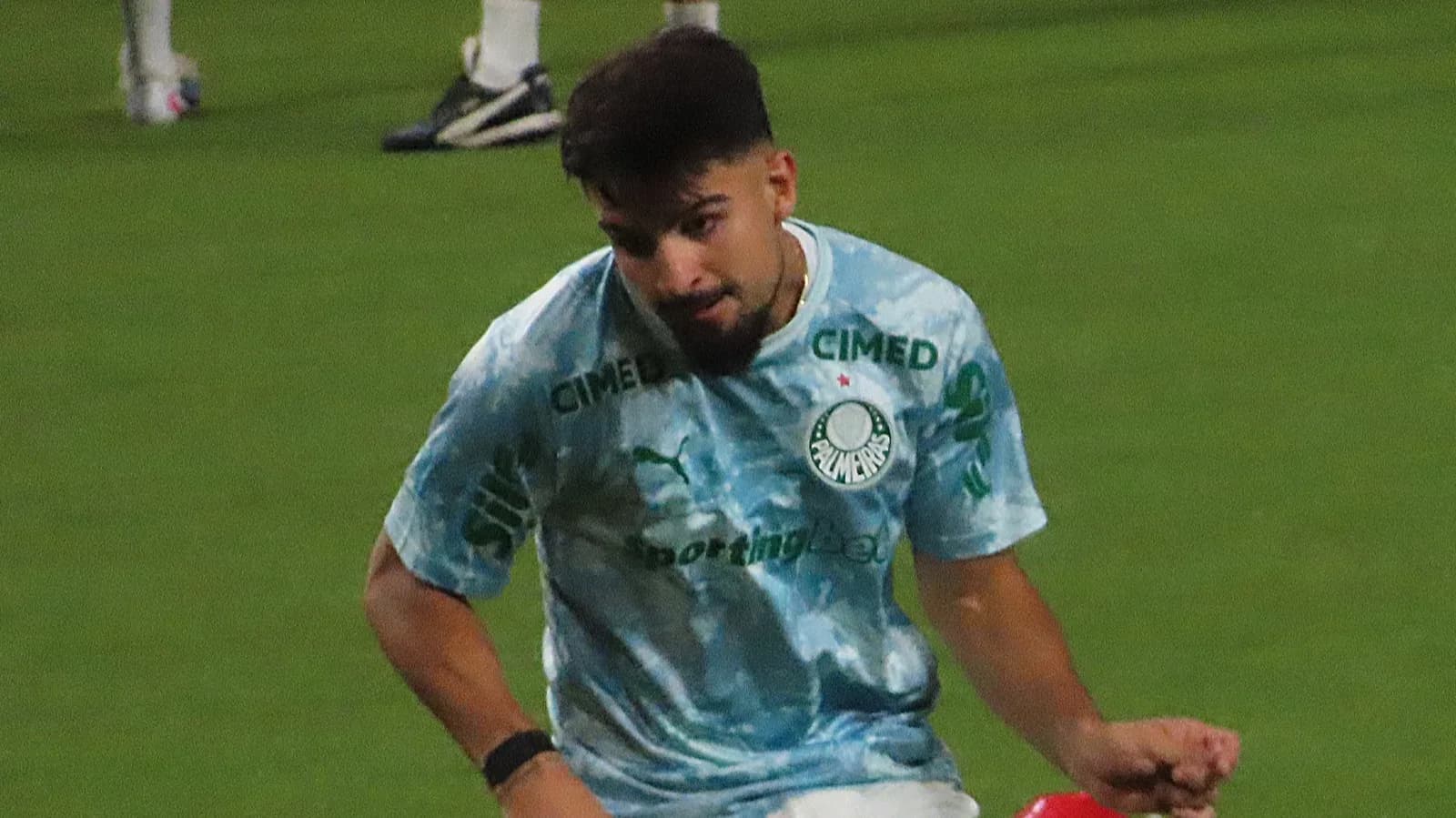 Jogador do Palmeiras com uniforme de treino, chutando a bola em campo