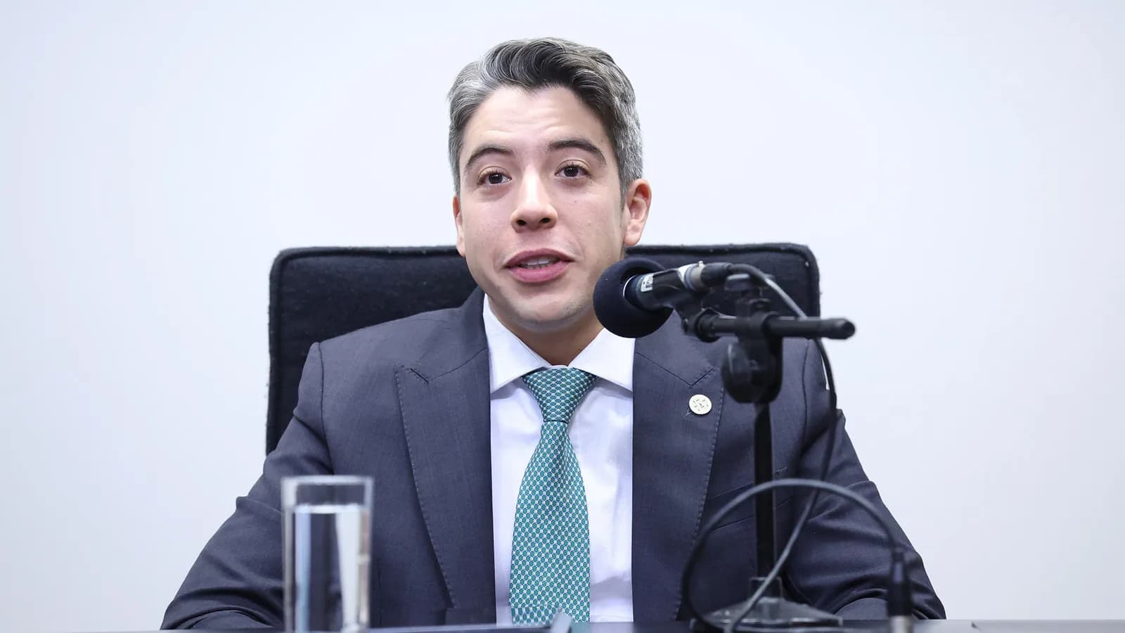 O deputado André Janones fala sentado em uma mesa durante sessão na Câmara dos Deputados