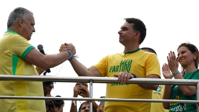 Flávio Bolsonaro de braço erguido ao lado do vice Alfredo Gaspar, em comício de lançamento da campanha em Copacabana