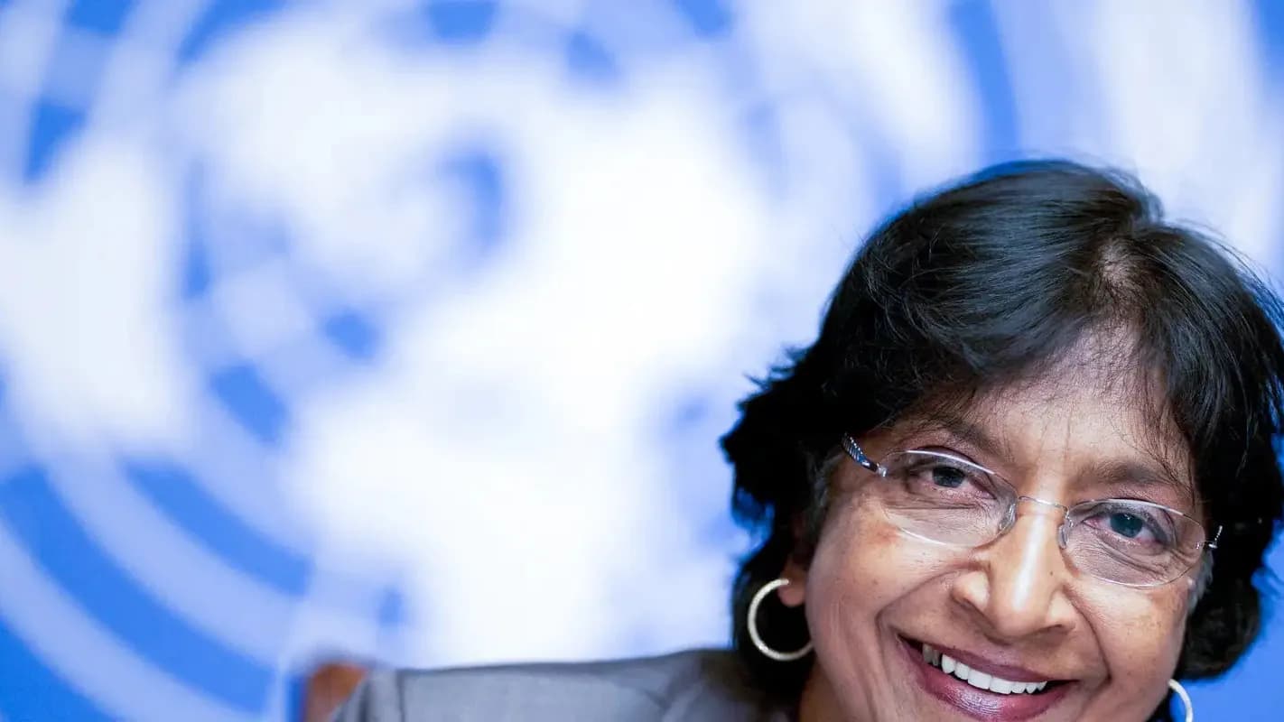 Navi Pillay sorri em evento internacional com bandeira da ONU ao fundo