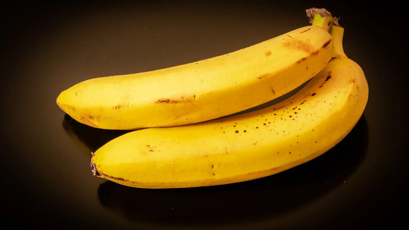 Cacho de bananas maduras sobre fundo escuro