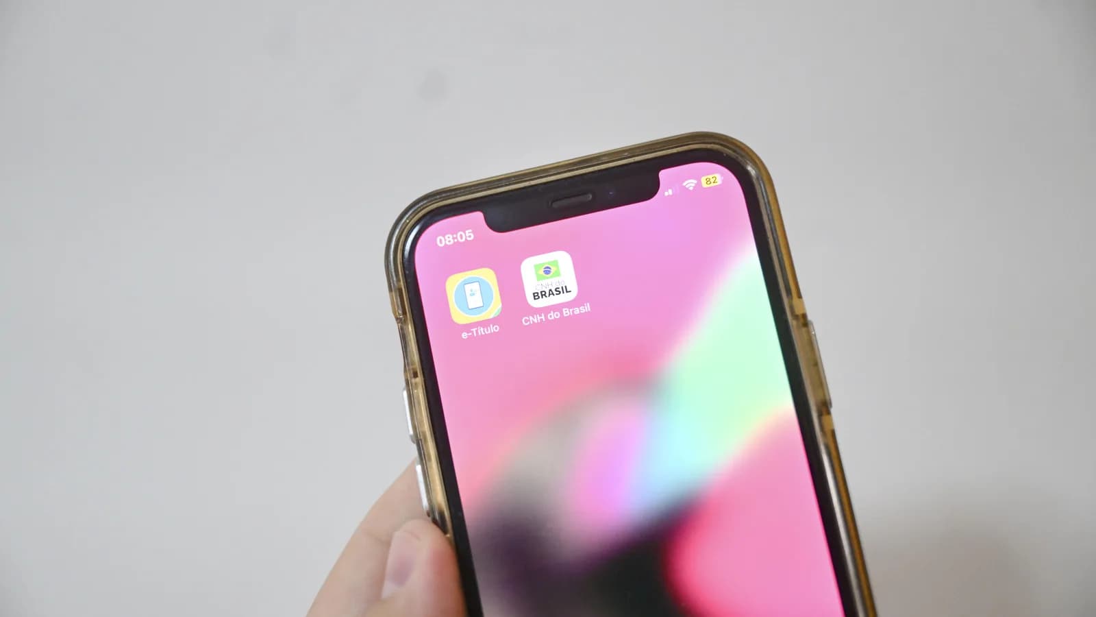 Mão segura celular com o aplicativo e-Título aberto, símbolo das Eleições 2026