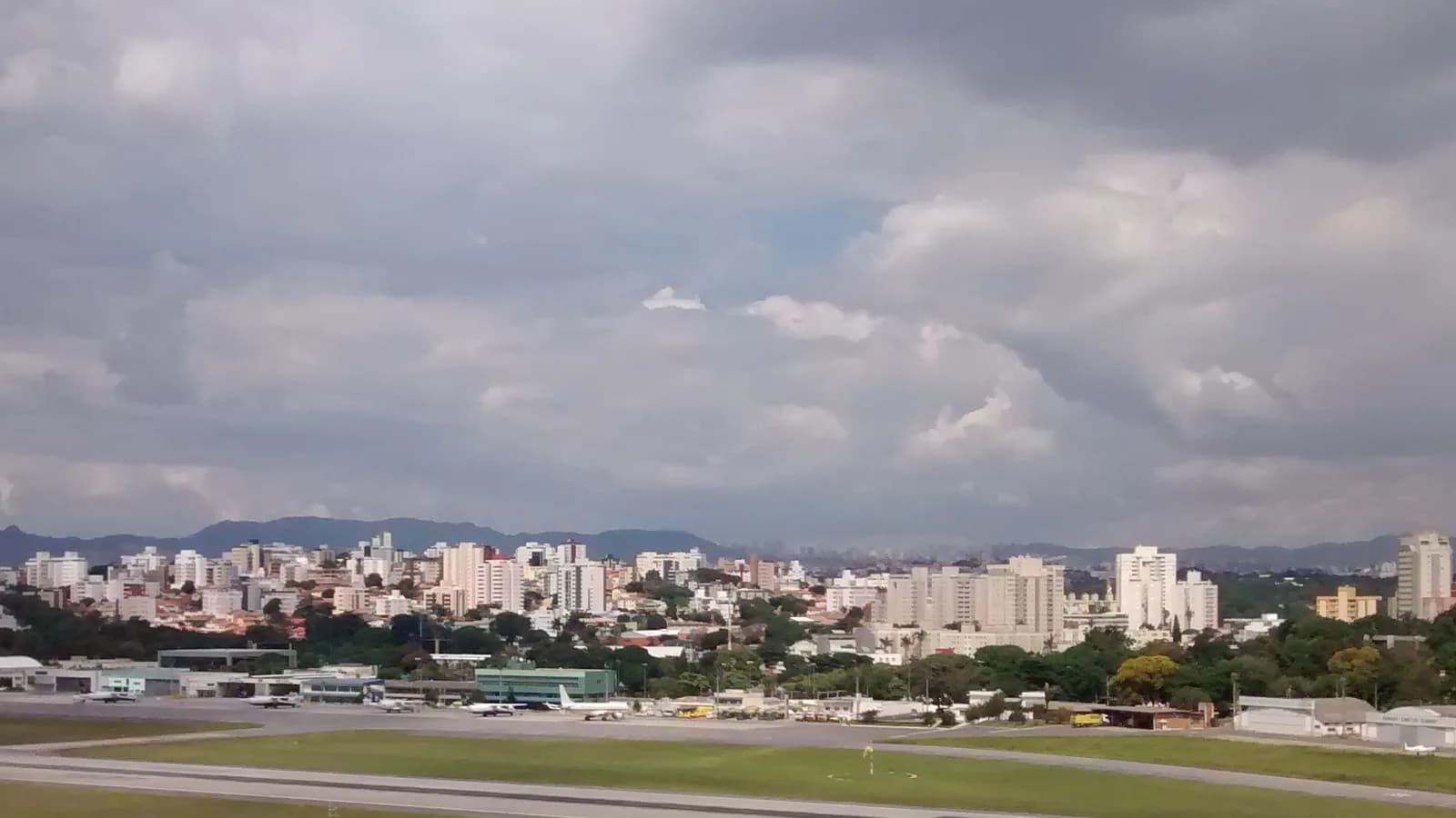 Vista aérea da pista do Aeroporto da Pampulha com a cidade de Belo Horizonte ao fundo