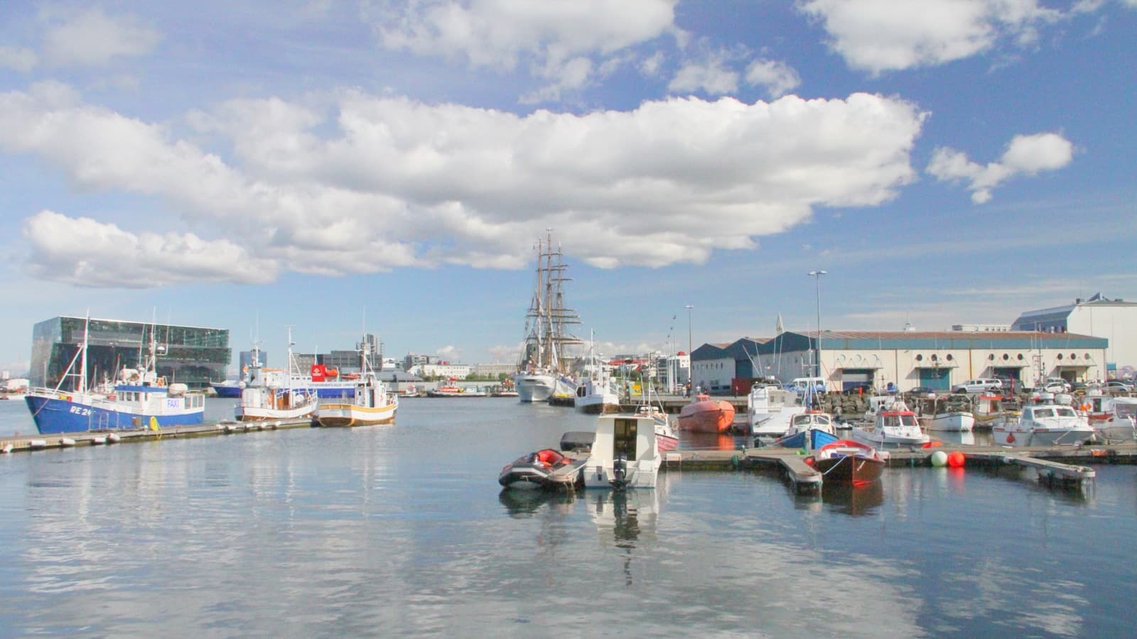 Barcos pesqueiros e outras embarcações atracados no porto de Reykjavík, na Islândia, sob céu azul; imagem de arquivo