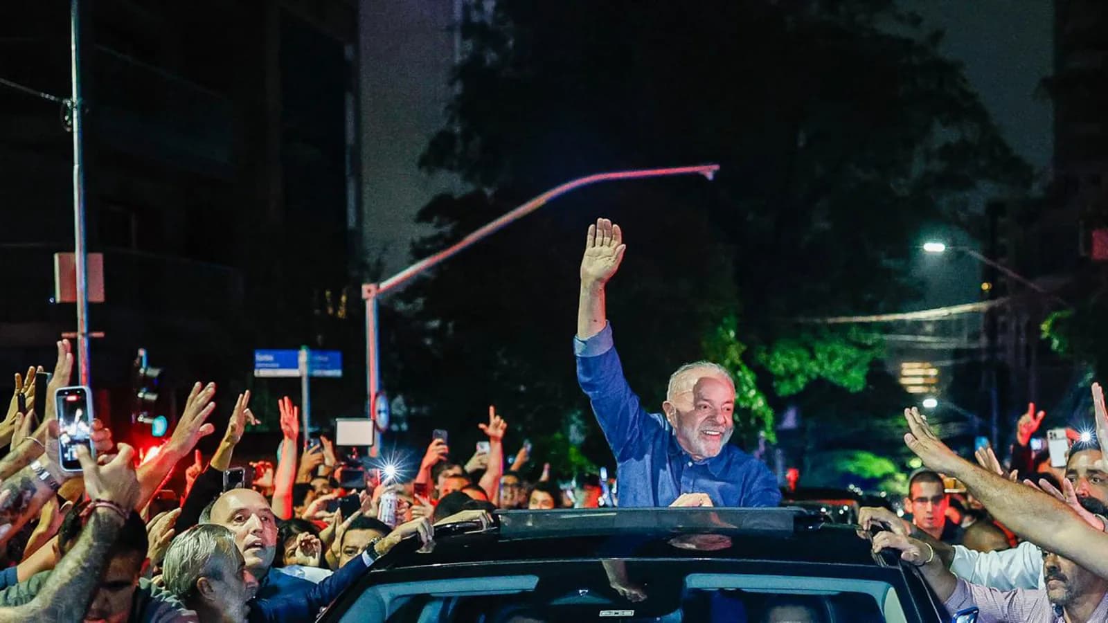Lula acena para a multidão em carro aberto durante ato de vitória à noite