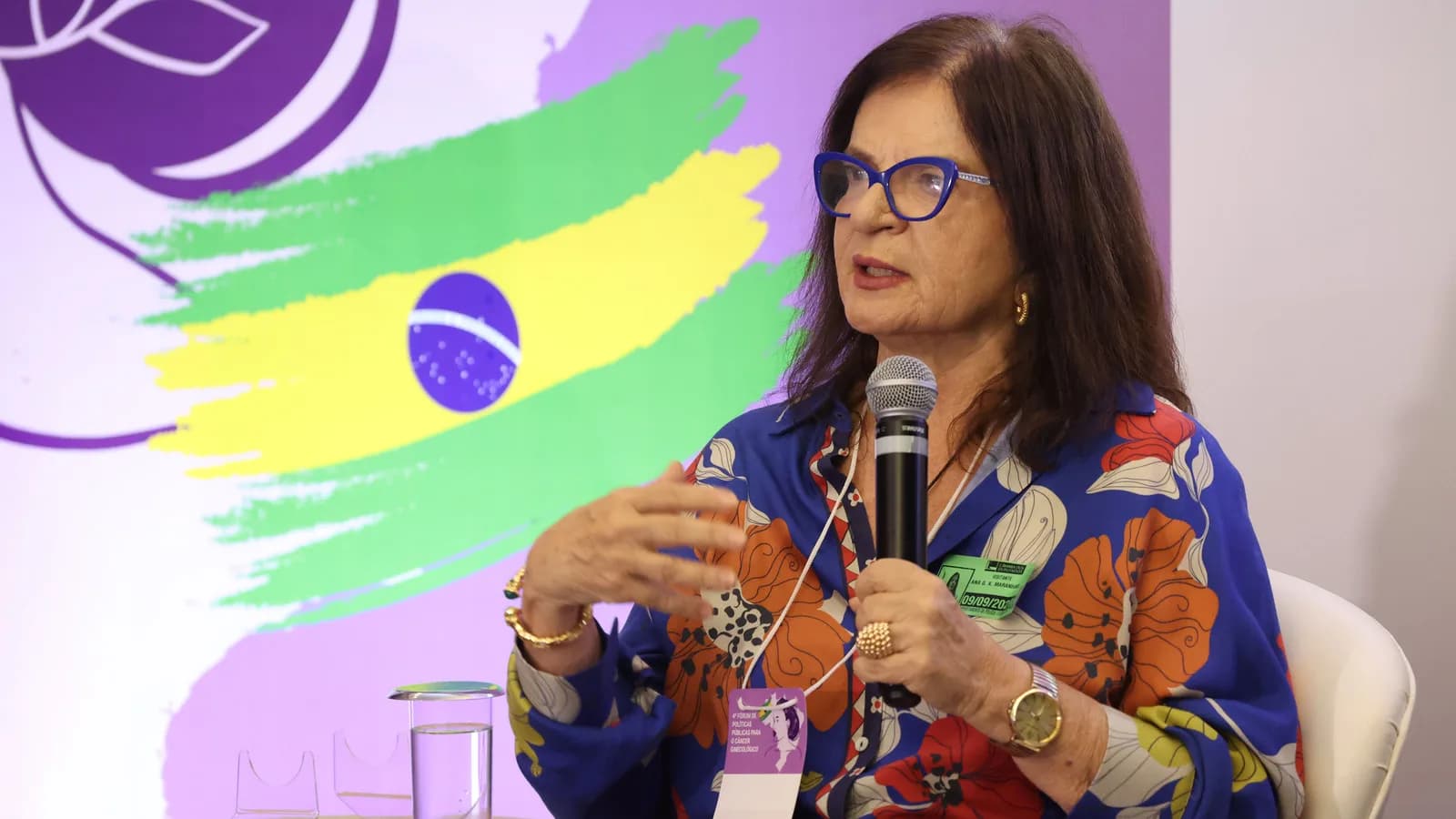 Médica fala ao microfone em fórum sobre saúde da mulher na Câmara dos Deputados
