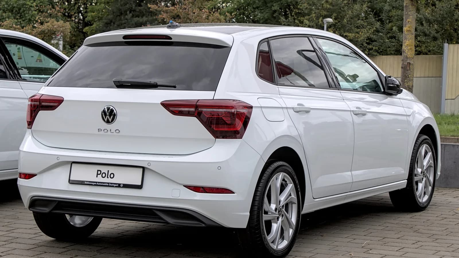 Volkswagen Polo branco visto de trás, estacionado em pátio