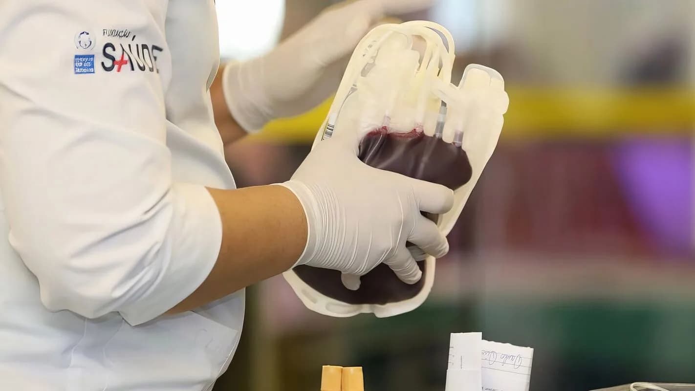 Profissional de saúde manuseia bolsa de sangue com luvas, foto ilustrativa de contexto hospitalar
