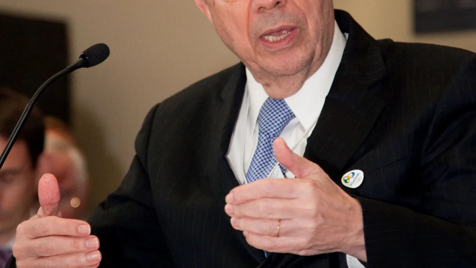Henrique Meirelles discursa gesticulando durante evento, com papéis na mão