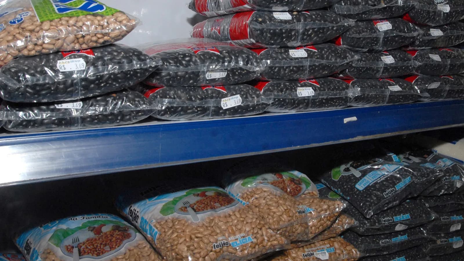 Pacotes de feijão empilhados em prateleira de mercado