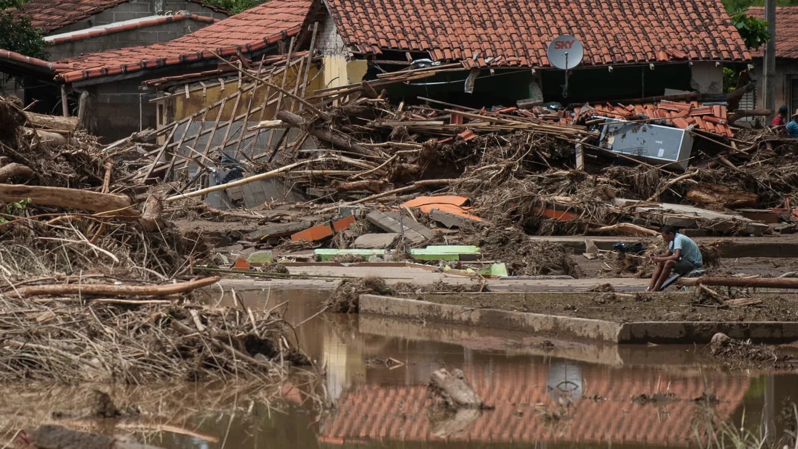 Casas destruídas por enchente no Vale do Ribeira, em São Paulo, com morador sentado entre os escombros (imagem de arquivo)