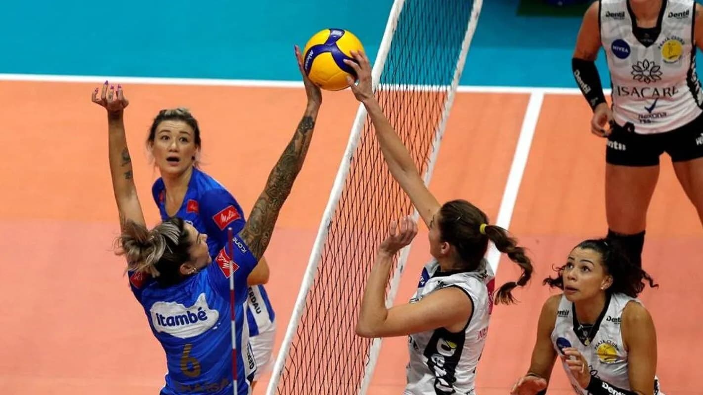 Jogadoras disputam bola no ataque em partida de vôlei