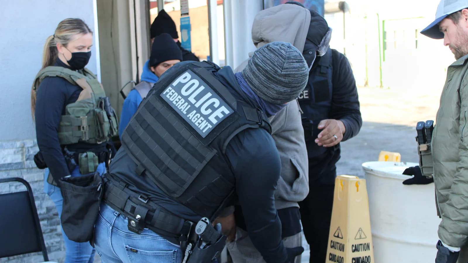 Agentes do ICE, com coletes identificados como 'POLICE' e 'ICE', durante operação de detenção nos Estados Unidos