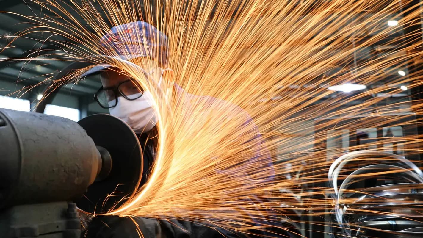 Trabalhador de indústria siderúrgica usa esmerilhadeira, com faíscas voando, em fábrica de aço