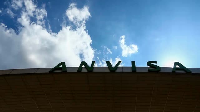 Letreiro com a palavra Anvisa na fachada do edifício-sede da Agência Nacional de Vigilância Sanitária, em Brasília, visto de baixo contra o céu azul