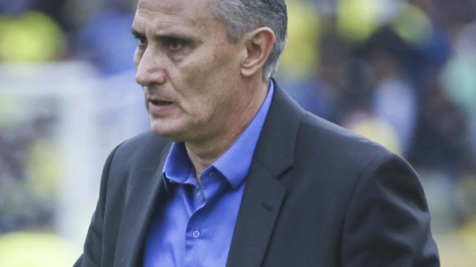 O técnico Tite observa o jogo com expressão séria durante partida da Seleção Brasileira