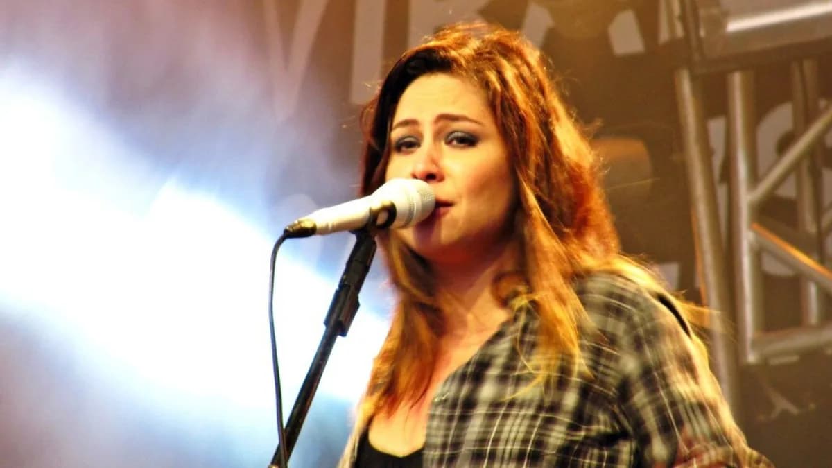 Pitty canta ao microfone durante show, com camisa xadrez, em foto de arquivo