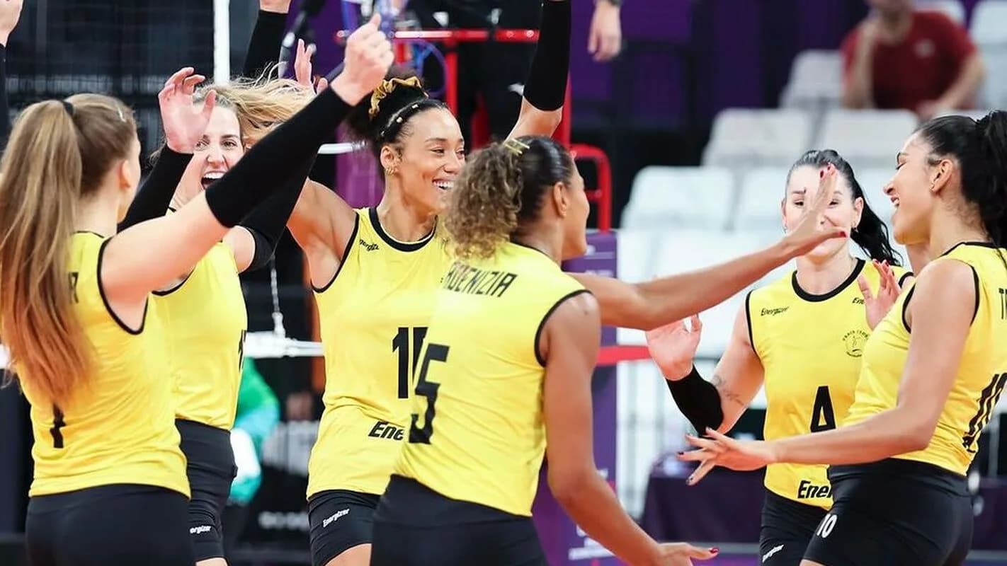 Jogadoras do Praia Clube comemoram ponto em partida de vôlei, uniforme amarelo e preto