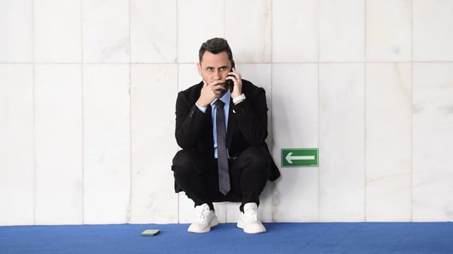 O senador Cleitinho, agachado e encostado em uma parede de mármore, fala ao celular em um corredor do Senado; imagem de arquivo