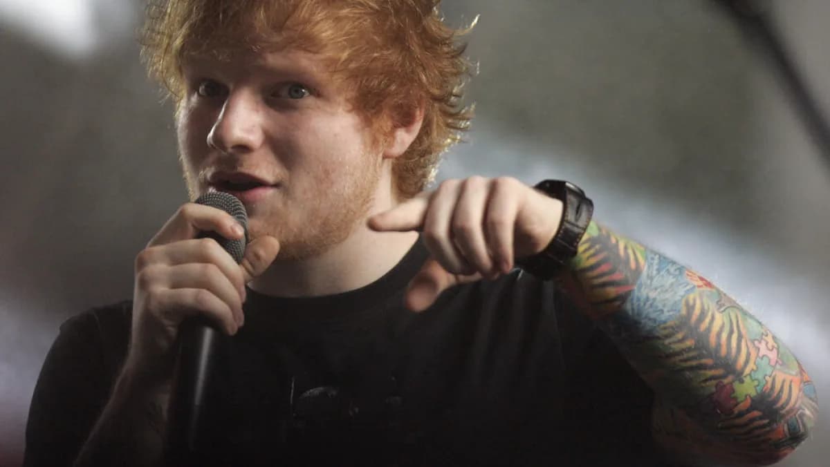 Ed Sheeran cantando ao microfone durante apresentação ao vivo