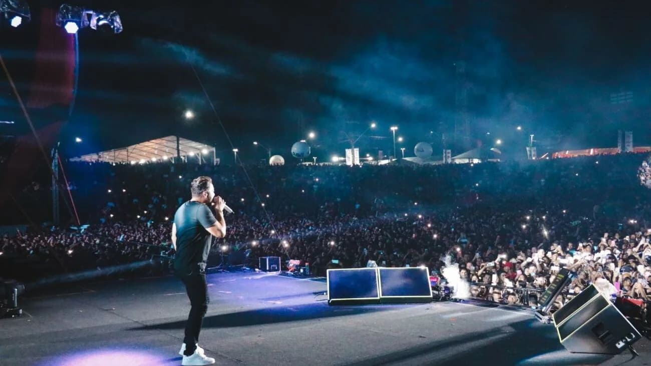 Cantor sertanejo se apresenta em palco de grande festival diante de multidão à noite