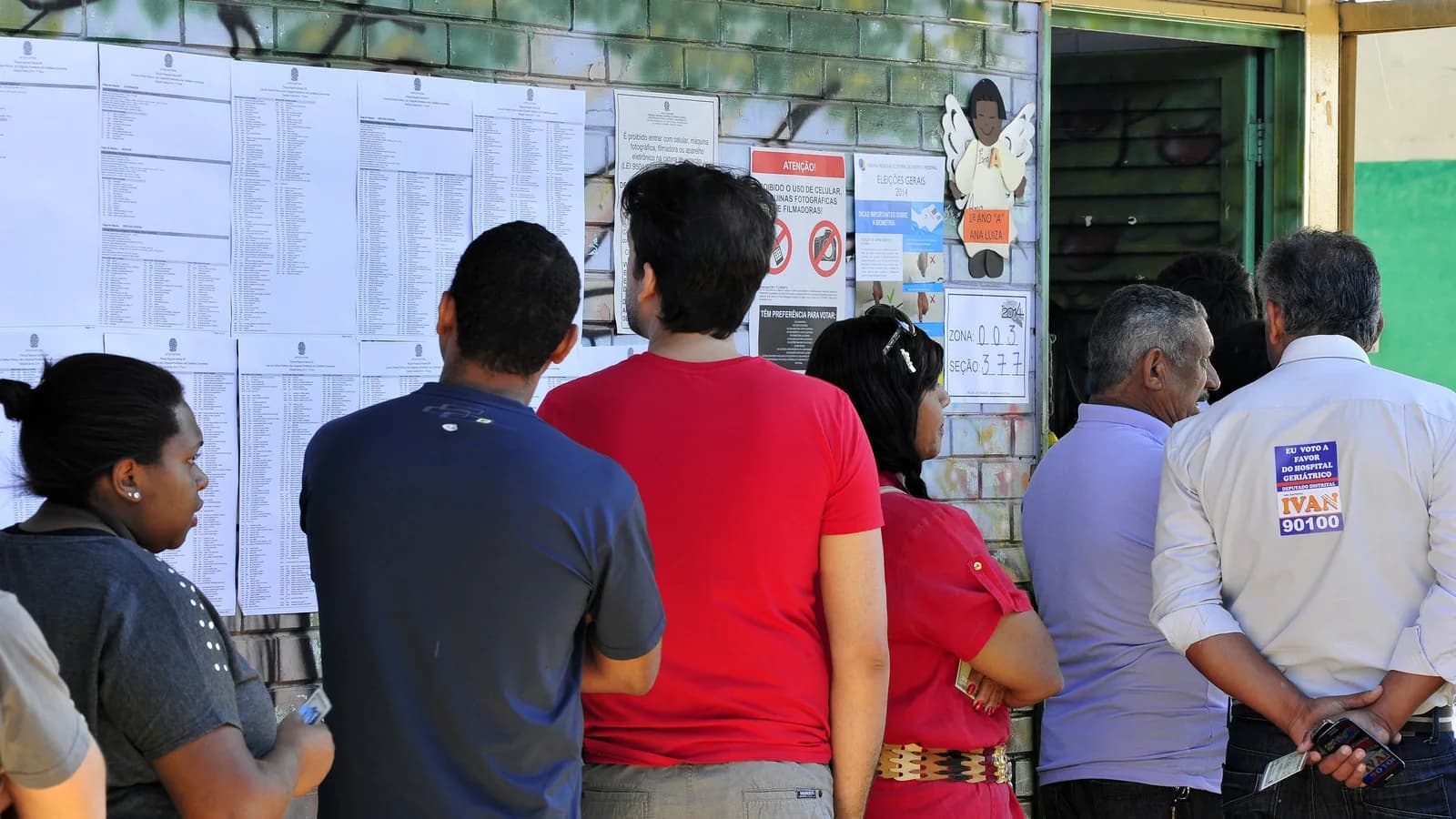 Fila de eleitores conferindo lista de votação em seção eleitoral