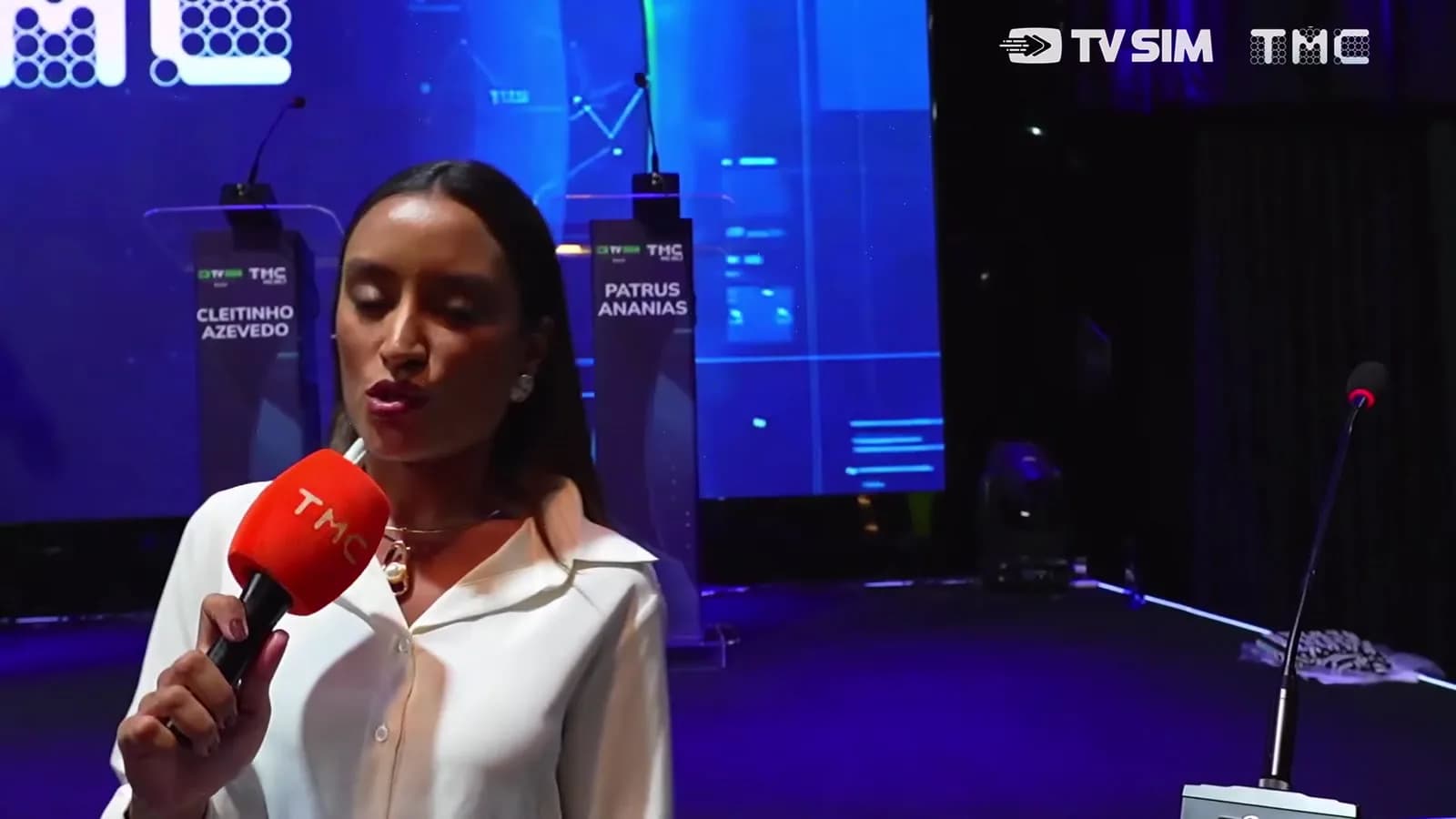 Repórter da TMC entrevista candidato em frente aos púlpitos vazios de Cleitinho Azevedo e Patrus Ananias antes do debate ao governo de Minas Gerais