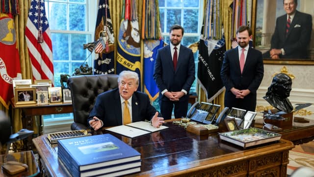 Foto de arquivo: o presidente dos Estados Unidos, Donald Trump, sentado à mesa do Salão Oval da Casa Branca durante a assinatura de uma ordem executiva, com dois auxiliares em pé ao fundo