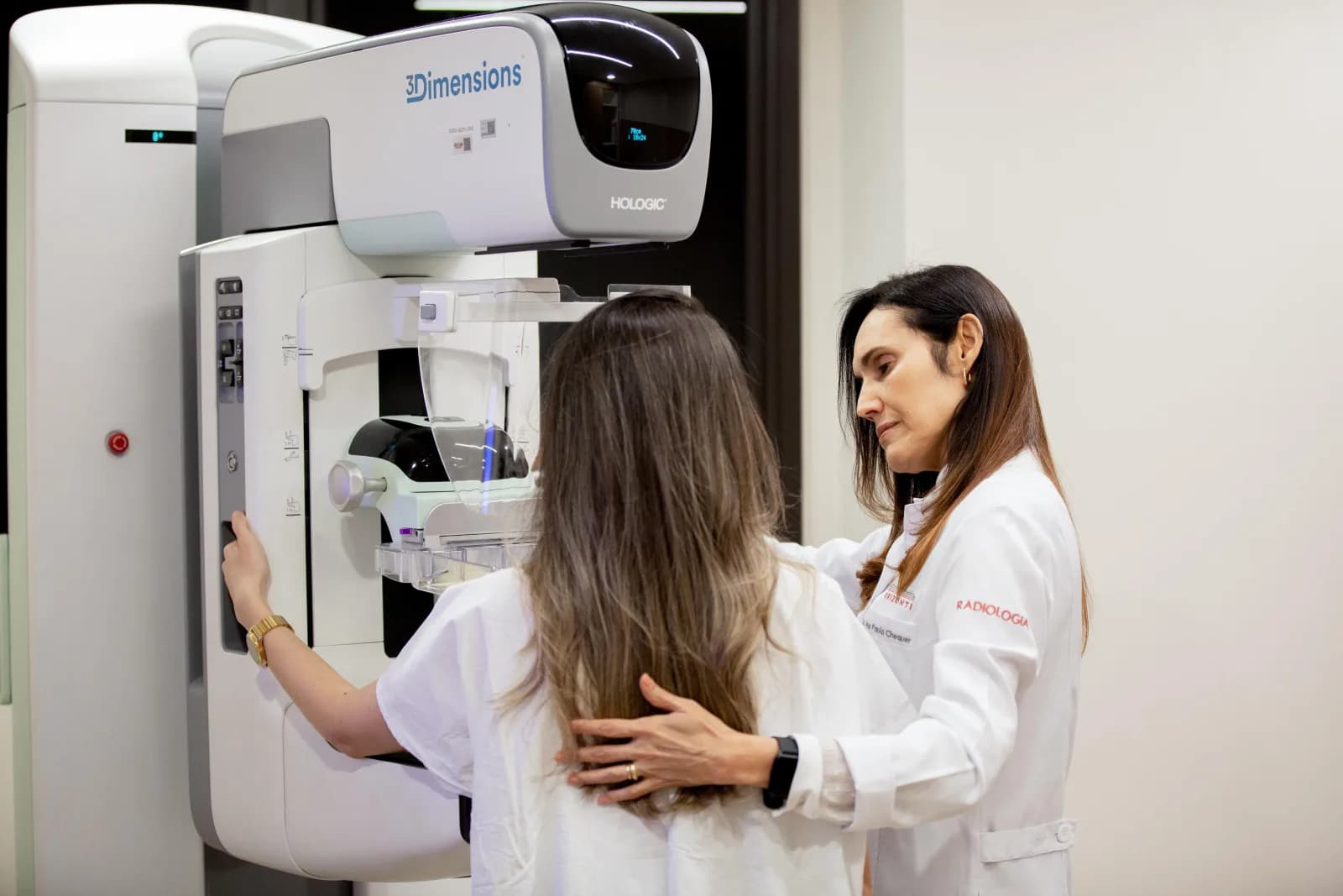 Profissional de saúde do Hospital Orizonti auxilia paciente durante exame de mamografia digital