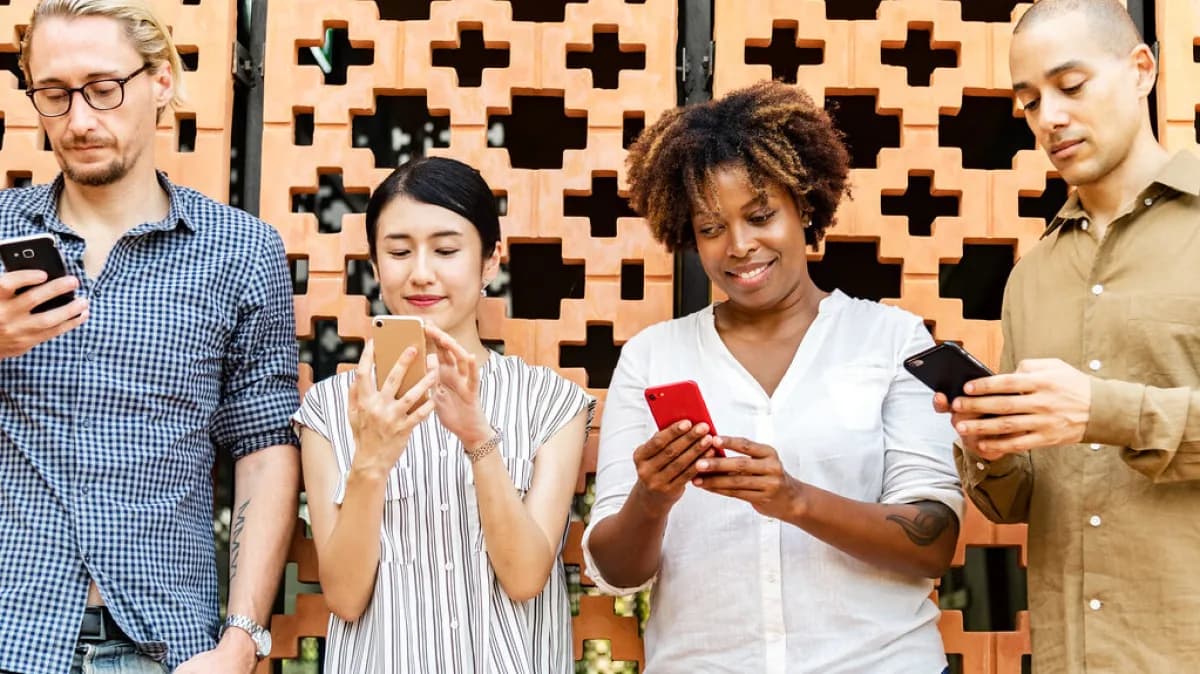 Grupo de quatro pessoas usando celulares lado a lado