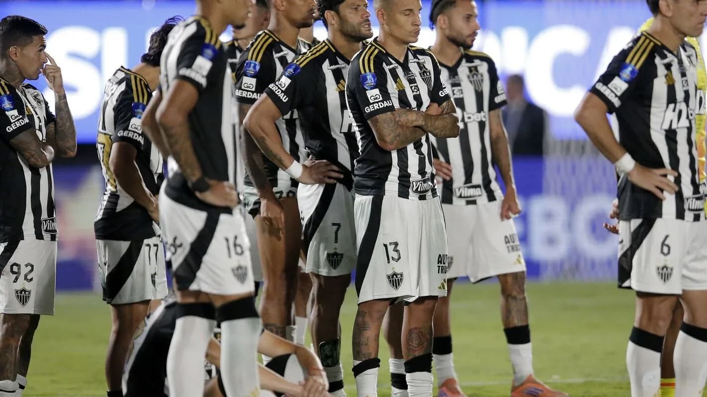 Jogadores do Atlético-MG perfilados em campo, com uniforme preto e branco listrado