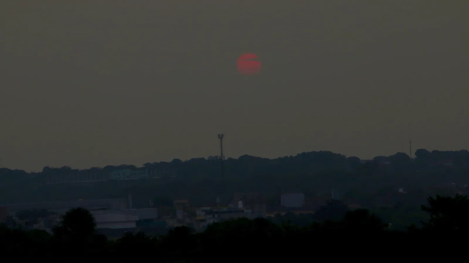 Sol avermelhado visto através da densa fumaça de queimadas sobre Manaus