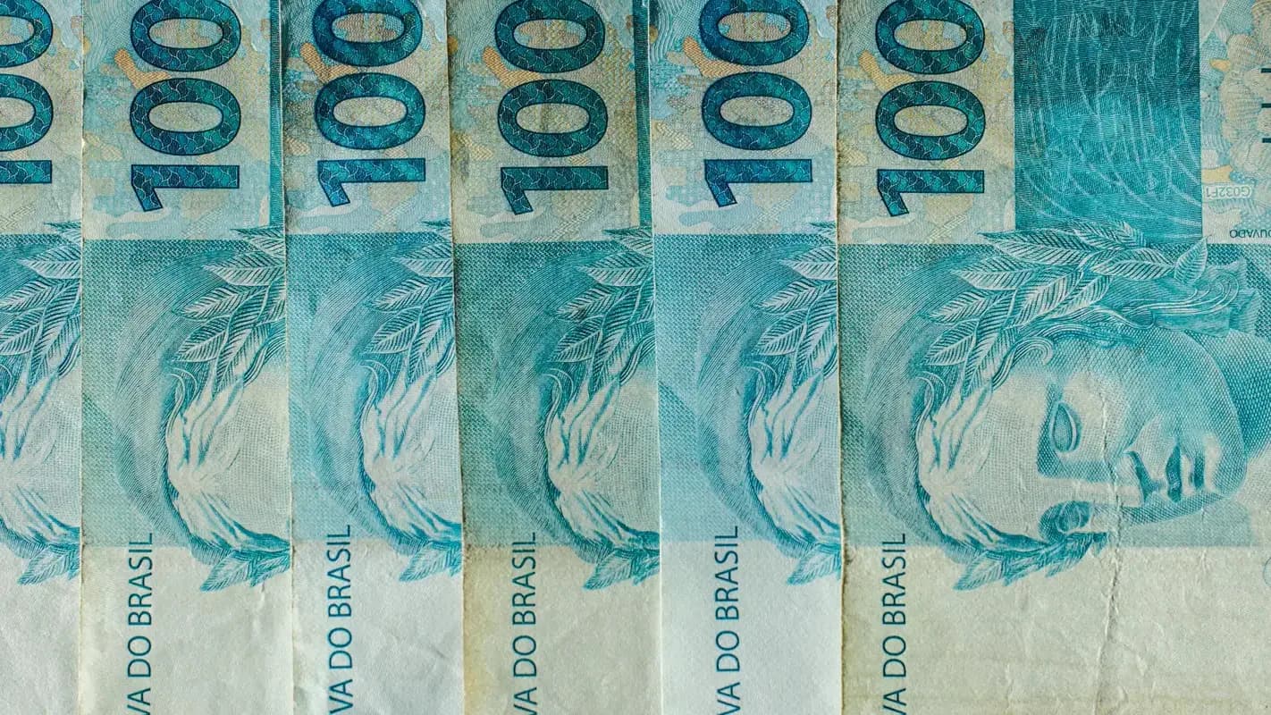Cédulas de R$ 100 organizadas, representando o cenário fiscal e de investimentos no Brasil