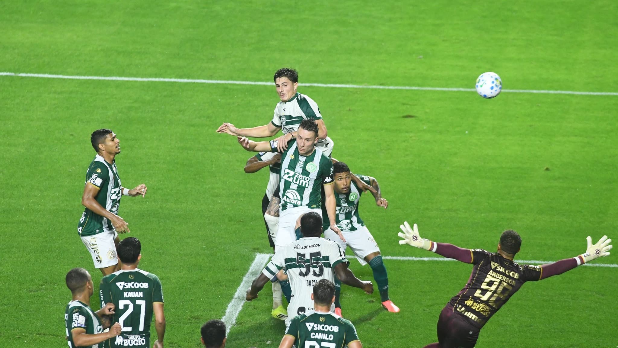 Jogadores de Coritiba e Chapecoense disputam bola aérea na área, com o goleiro da Chapecoense se esticando para afastar