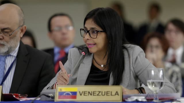 Delcy Rodríguez fala ao microfone em reunião internacional, com placa da Venezuela à frente