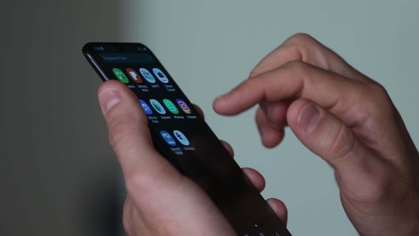 Mãos segurando e mexendo em um smartphone com aplicativos, em close
