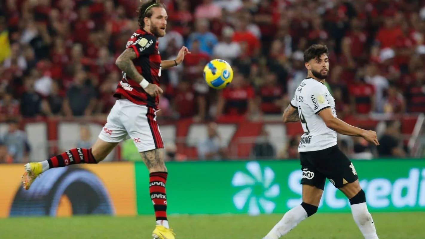 Jogador do Corinthians disputa bola com jogador do Flamengo em campo