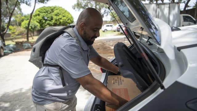 Trabalhador organiza urnas eletrônicas no porta-malas de um carro para distribuição às seções eleitorais