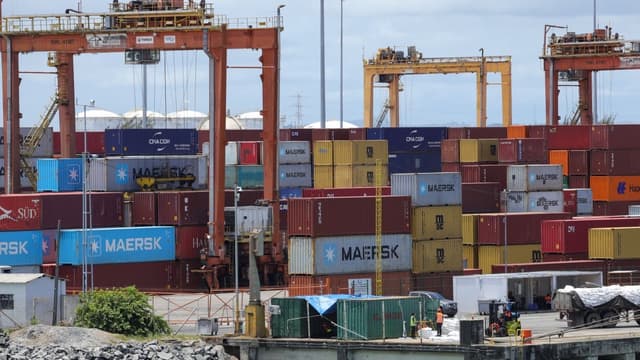 Contêineres empilhados em terminal portuário, com guindastes ao fundo, ilustrando o comércio exterior brasileiro afetado pelo tarifaço dos EUA