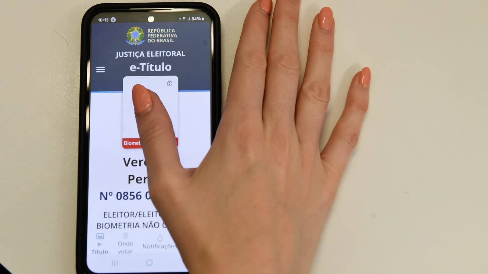 Pessoa usa o aplicativo e-Título no celular, com biometria
