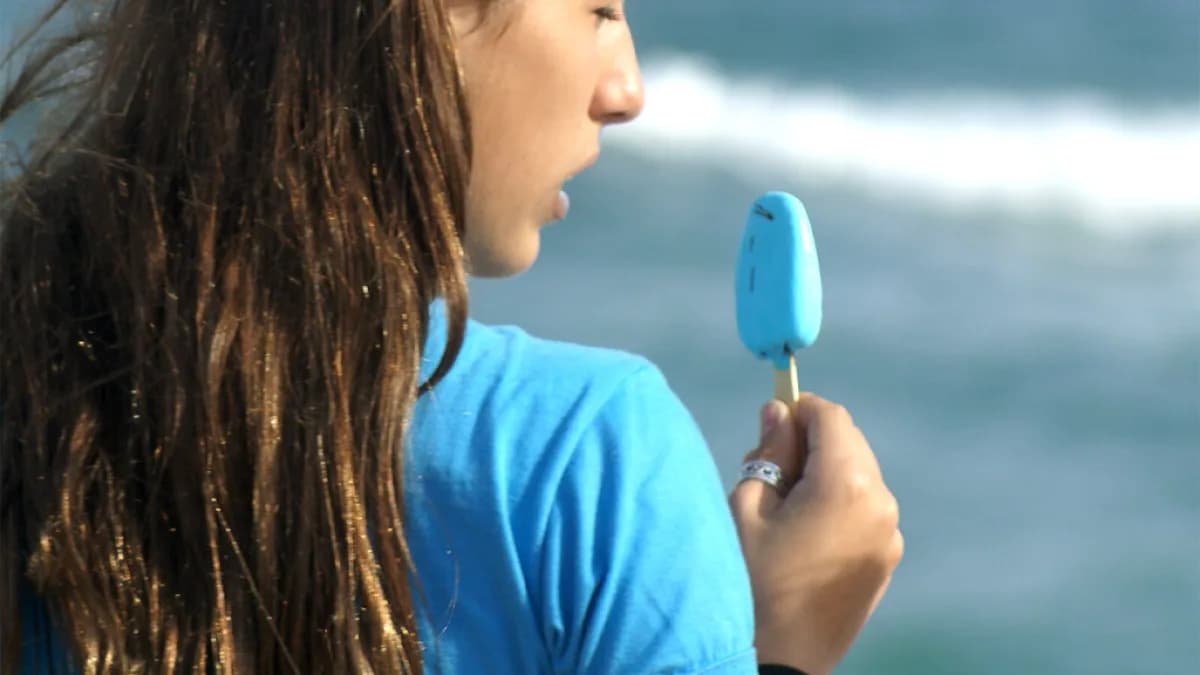 Jovem come picolé gelado à beira-mar