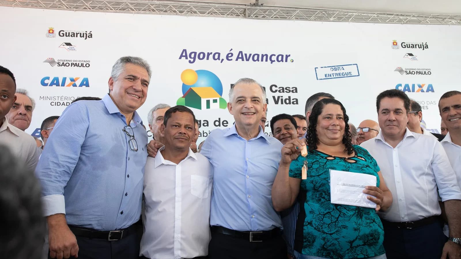 Beneficiária exibe chaves ao lado de autoridades durante entrega de moradias no Guarujá, em abril de 2018, em foto de arquivo.