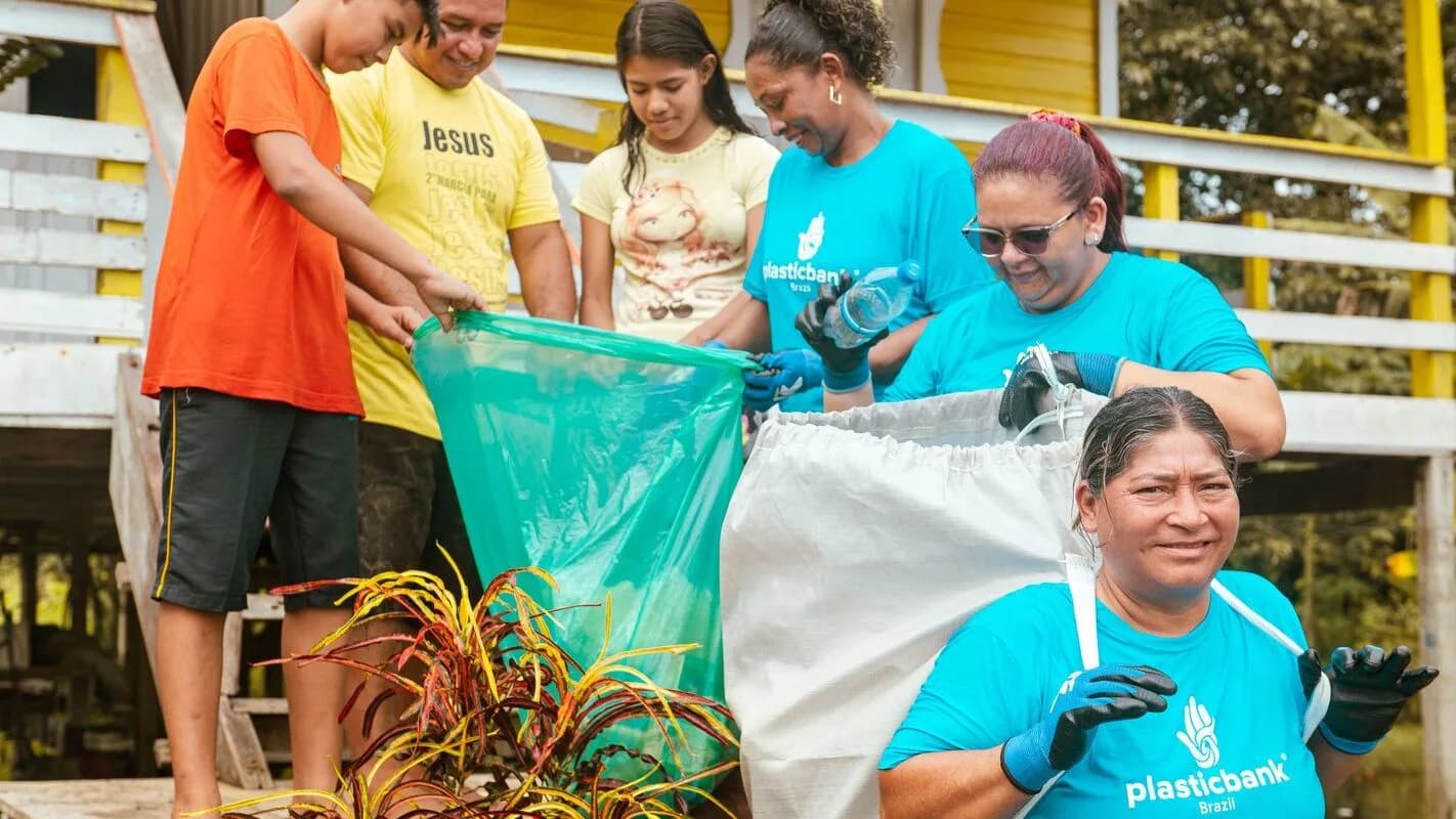 Grupo de pessoas separando material reciclável, incluindo plásticos, em programa de coleta