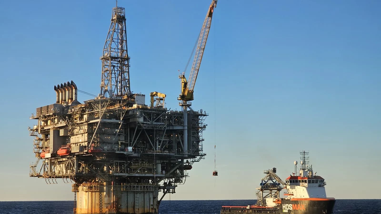 Plataforma de petróleo e gás no mar, com embarcação de apoio ao lado