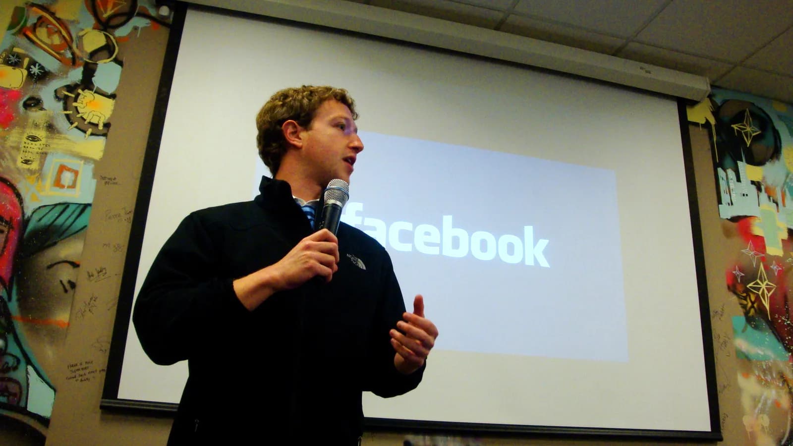 Mark Zuckerberg fala ao microfone durante apresentação com o logo do Facebook ao fundo