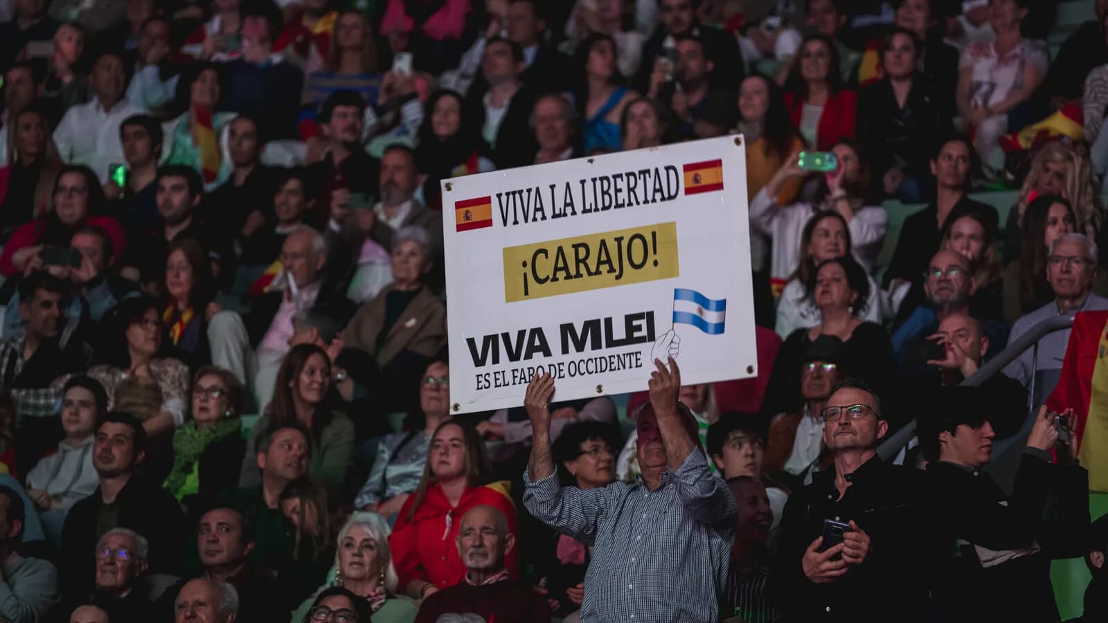 Multidão segura cartazes com os dizeres 'Viva Milei' em evento político na Espanha