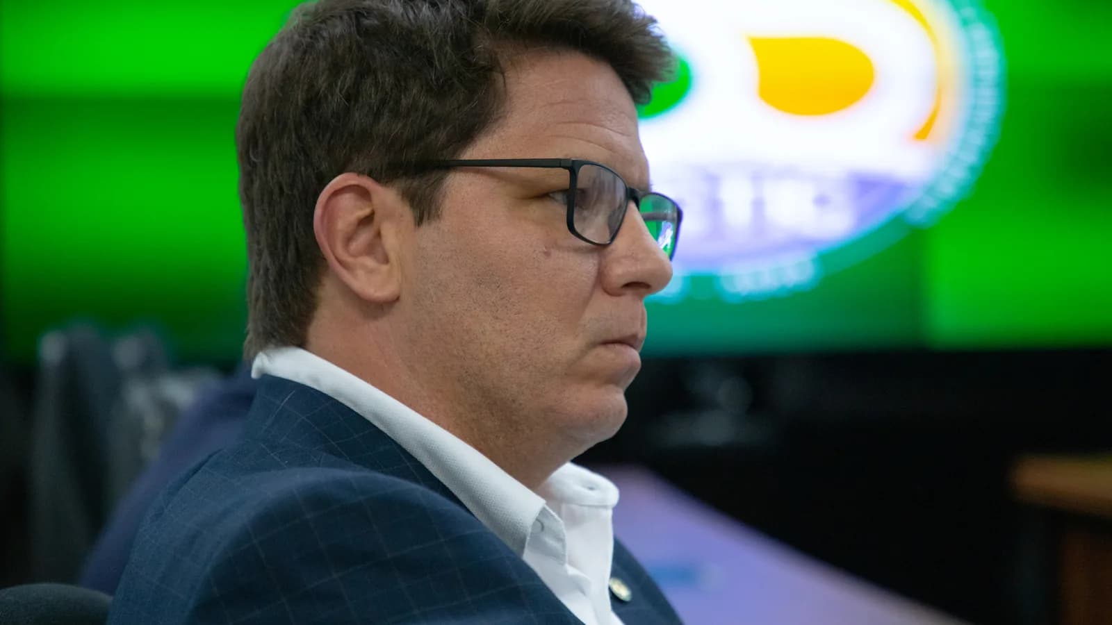 Mario Frias em reunião, de terno, olhando para o lado