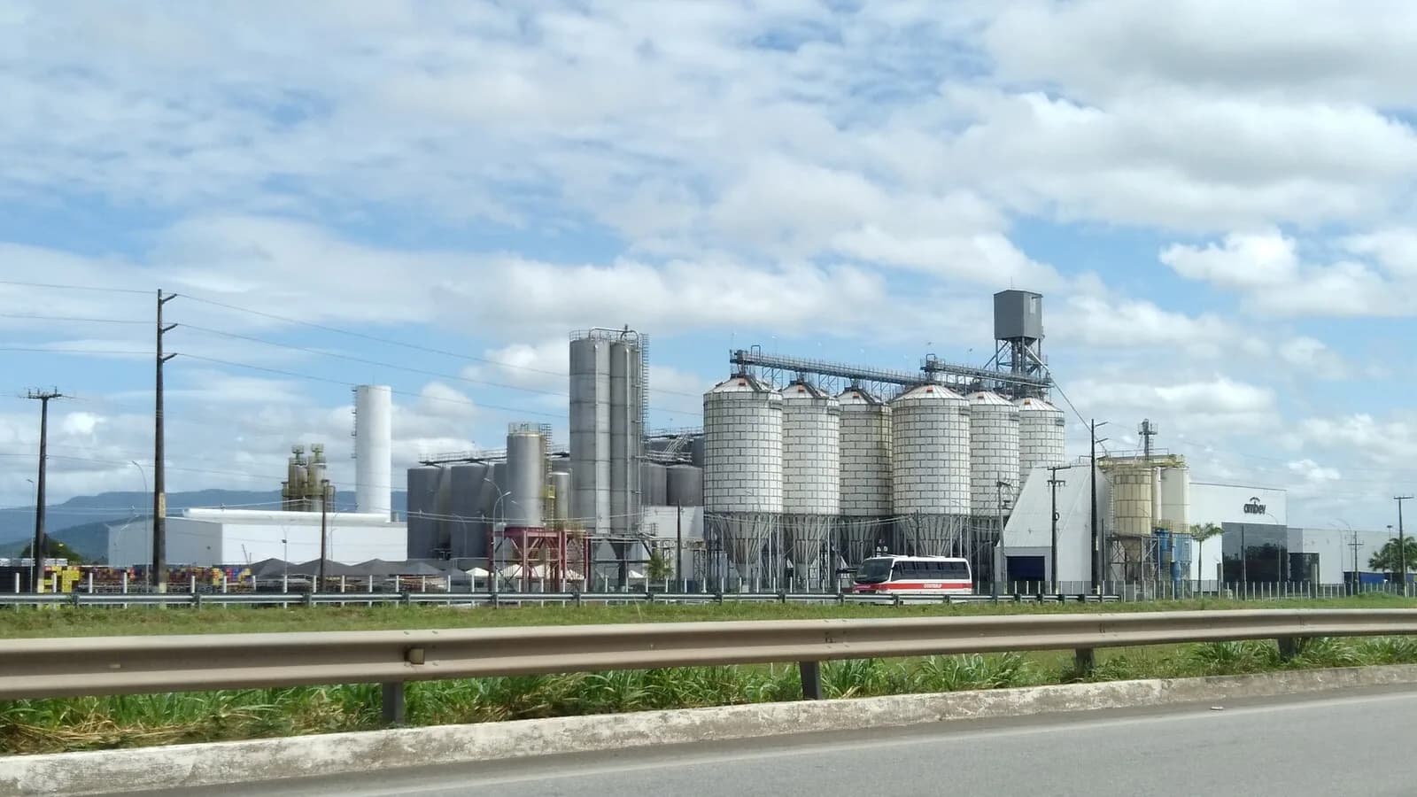 Fábrica da Ambev com silos e tanques industriais, vista da rodovia