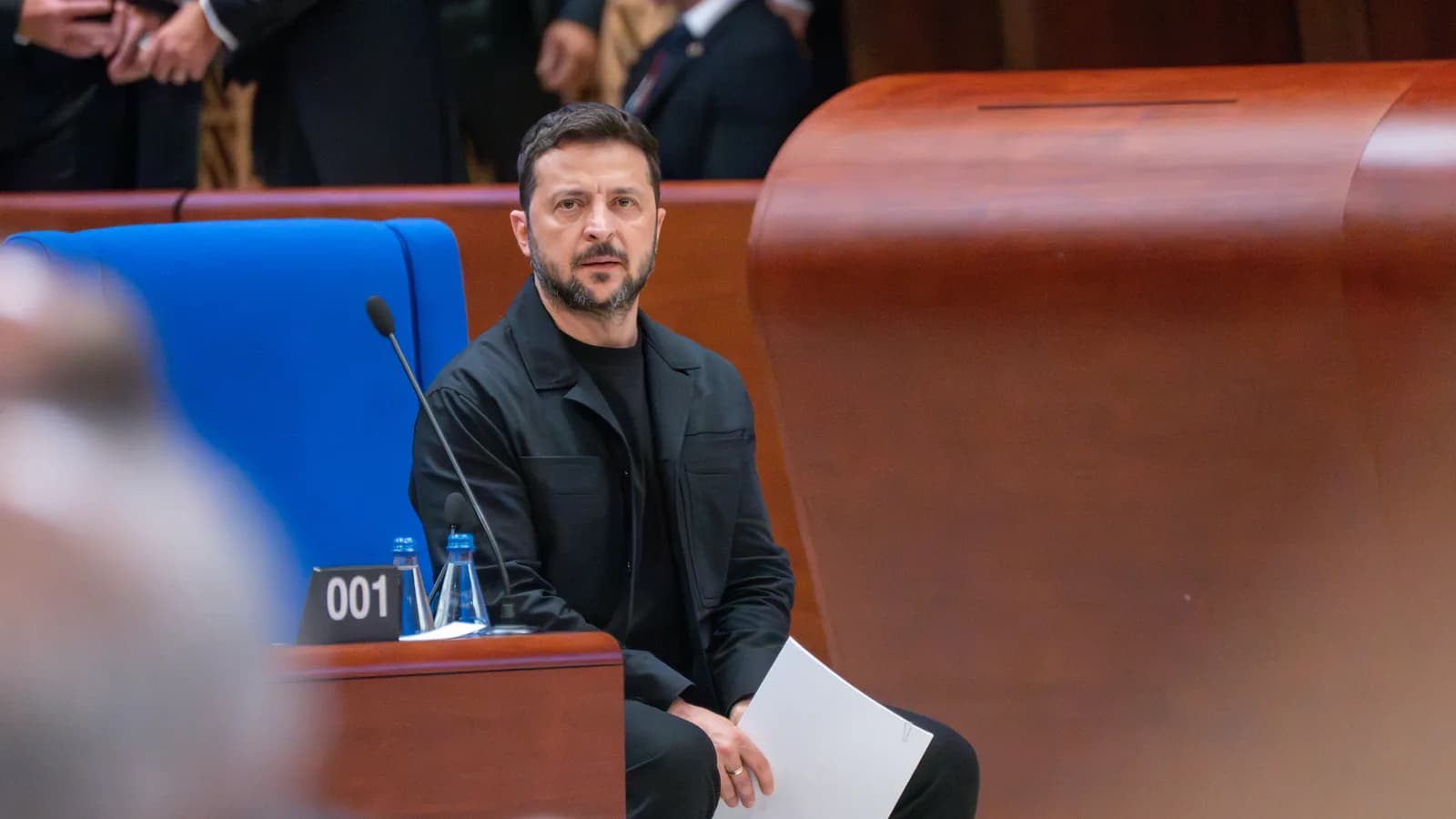 O presidente da Ucrânia, Volodymyr Zelensky, sentado e sério durante evento no Conselho da Europa