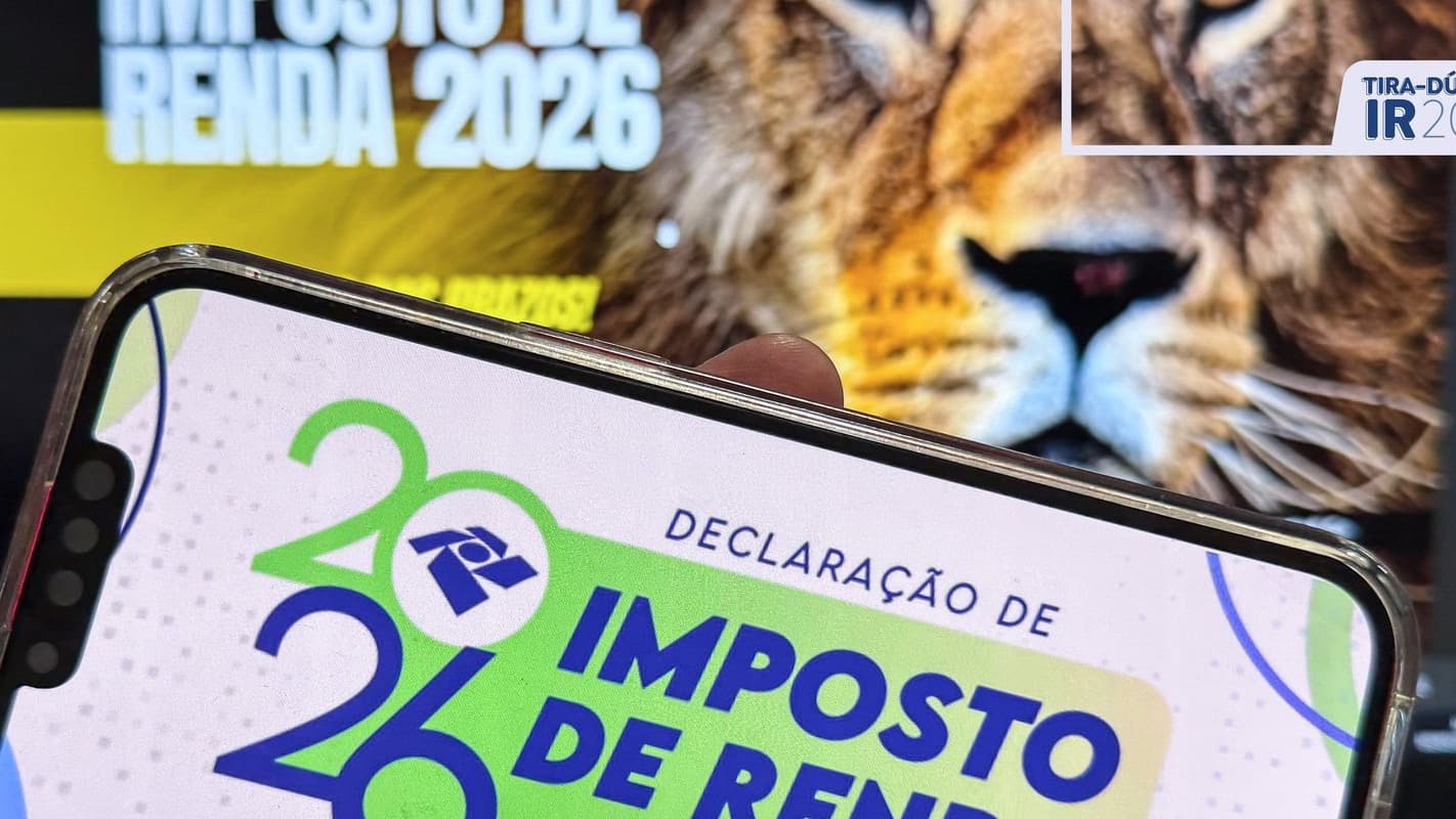 Imagem de arquivo: celular exibe a tela da Declaração de Imposto de Renda 2026, com o logotipo da Receita Federal; ao fundo, peça da campanha do IR 2026 com a imagem de um leão